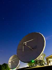 Weltraumbeobachtung Zwei Radaranlagen mit riesigen Satellitenschüssel von unten fotografiert vor einem Sternenhimmel.