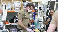 Ein Soldat behandelt einen vor sich liegenden Patienten