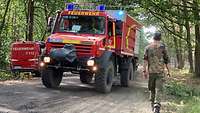 Ein Soldat läuft an einem fahrenden Feuerwehr-Fahrzeug vorbei. 