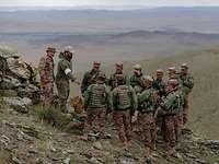 Erläuterungen am Geländesandkasten Ein deutsche und mehrere mongolische Soldaten stehen in der Steppe an einem taktischen Sandkasten.