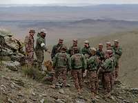 Ein deutsche und mehrere mongolische Soldaten stehen in der Steppe an einem taktischen Sandkasten.