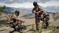 Drei mongolische Soldaten überprüfen auf einer Anhöhe die eigene Kletterausrüstung. 