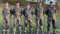Fünf Soldaten stehen in Feldanzug im Grünen mit Bäumen im Hintergrund