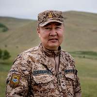 Ein Stabsoffizier steht lächeln in der mongolischen Steppe.