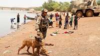 Ein Soldat mit seinem Hund am Flussufer