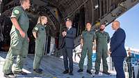 Bundeskanzler Olaf Scholz steht mit fünf Soldaten auf der Laderampe des Transportflugzeuges A400M