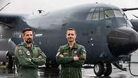 Ein deutscher und ein französischer Pilot stehen nebeneinander vor dem neuen Transportflugzeug C-130J