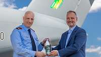 Zwei Männer präsentieren eine Flasche mit Nachhaltigkeitslogo