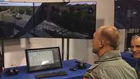Ein Pilot sitzt an einem Simulator vor mehreren Bildschirmen.
