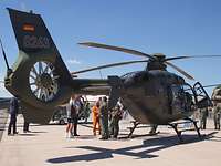Im Austausch Ein Hubschrauber steht auf einem Flugfeld. Der Pilot und Besucher im Gesräch