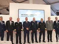 ILA22 Soldaten und zivile Vertreter der Industrie stehen in einer Reihe nebeneinander vor einem Bildschirm