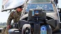 Ein amerikanischer Soldat sitzt auf einem Kampfhubschrauber des Types Apache