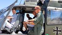 Ein Pilot erklärt, wie ein Hubschrauber fliegt, während drei Zivilisten im Hubschrauber sitzen