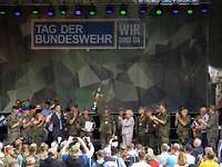 Soldaten und Zivilisten stehen applaudierend auf einer Bühne. Ein Soldat auf der Bühne hält einen Pokal in die Luft.