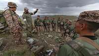 Ein deutscher Soldat erklärt mehreren mongolischen Soldaten etwas in der Steppe.