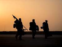 Die letzten Soldaten verlassen Afghanistan Drei Soldaten laufen mit Gepäck bei tiefstehender Sonne über den Flugplatz.