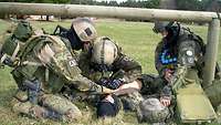 Kampfschwimmer Verletztenversorgung Drei Soldaten versorgen einen verletzten Soldaten.