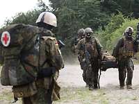 Kampfschwimmer mit einem Verletzten Vier Soldaten schleppen einen verletzten Soldaten auf einer Trage.