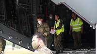 Eine Soldatin geht mit Papieren in der Hand aus der Heckklappe eines Transportflugzeugs A400M.