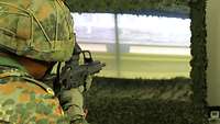 Ein Soldat zielt mit einem Gewehr G36 auf eine Leinwand.