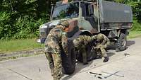 Eine Gruppe Soldaten wechselt einen Reifen an einem LKW. 