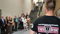 Ein Soldat im Sportshirt im Vordergrund, dahinter Gäste bei der Eröffnung.