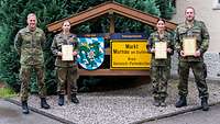 Soldatinnen und Soldaten wurden ausgezeichnet und halten ihre Urkunden zum Gruppenbild vor dem dem Körper. 