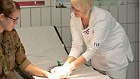 Eine Sanitäterin die eine Hand anguckt 