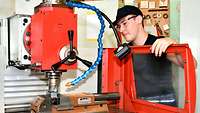 Ein Junger Mann mit Schutzbrille arbeitet an einer Werkbank.