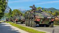 Auf einer Landstraße fahren mehrere Fahrzeuge der Bundeswehr hintereinander.