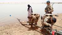 Drei Soldaten und ein Zivilist am Niger arbeiten an einer Pumpe