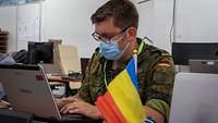 Ein deutscher Soldat der Bundeswehr vor einer rumänischen Flagge