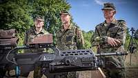 Einige Lehrgangsteilnehmer stehen vor einem aufgestellten Gewehr G36 und hören einem Ausbilder zu.