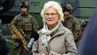 Ministerin Lambrecht spricht in ein Mikrofon. Im Hintergrund stehen Soldaten.