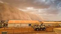 Eine riesige Staubwolke rollt über ein Bundeswehr-Camp