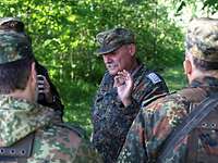 Ein Soldat steht vor einer Gruppe anderer Soldaten und spricht