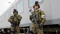 Zwei Soldaten im Feldjägerdienst stehen mit ihren Waffen vor einem Bahnwaggon.