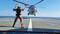 Flugoffizier hält zwei Flaggen in die Luft, um Helikopter Anweisungen zu geben.