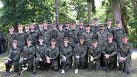 25 junge Frauen und Männer in Uniform hocken und stehen für ein Gruppenbild.