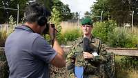 Ein Soldat hält ein Mikrofon in der Hand und wird von einem Journalisten gefilmt.