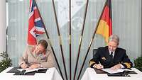 Vizeadmiral Dr. Daum und Lieutenant General Copinger-Symes unterzeichnen feierlich Dokumente