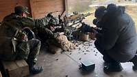Zwei Soldaten liegen mit MG5 in Stellung, ein Soldat zeigt auf das Ziel, ein Kameramann filmt sie.
