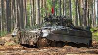 Ein Schützenpanzer Marder fährt durch tiefen Sand. Im Hintergrund stehen Bäume.