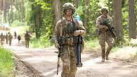 Niederländische Soldaten in Kampfausrüstung marschieren zu Fuß einen Waldweg hoch