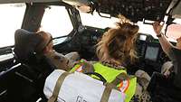 Eine Ärztin steht im Cockpit eines A400M hinter einem Soldaten, der scheinbar bewusstlos im Pilotensitz sitzt