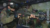 Ein Soldat steht in einem Trainingraum mit einer VR-Brille und Übungsgewehr. Hinter ihm steht ein weiterer Soldat.