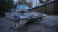 Ein Fahrschulpanzer der Bundeswehr steht auf einem Übungsgelände in der Dämmerung.