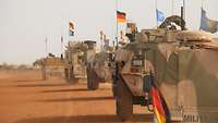 Mehrere geschützte Fahrzeuge der Bundeswehr fahren im Konvoi durch die Wüste