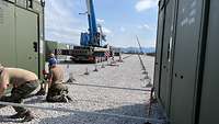 Zwischen zwei Containern hocken drei Soldaten