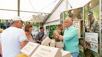 Ein Mann in Zivil steht an einem Info-Stand und erklärt Besuchern die Marschverpflegung der Bundeswehr